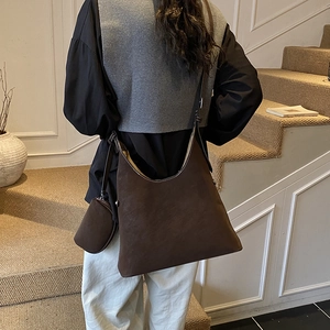 Detail of deep brown suede hobo bag with matching coin purse on a shoulder