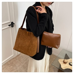 Detail view of brown faux suede tote bag and matching clutch set with golden metal hardware