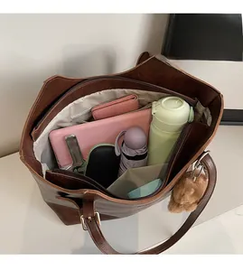 Detailed view of spacious dark brown tote bag interior with teddy bear charm