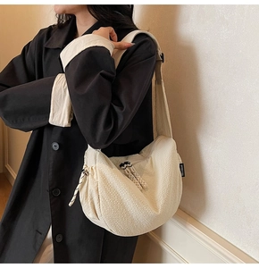 Detail der cremefarbenen Halbmond-Stofftasche mit Waffelstruktur und breitem Gurt