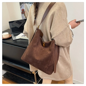 Close-up of brown suede tote bag featuring adjustable leather strap and golden metal buckle
