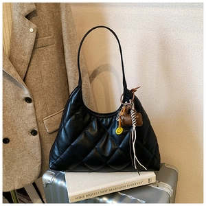 Detailed close-up of quilted black hobo bag with yellow smiley face and tassel charms