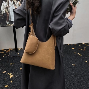Detail of tan suede crescent bag with matching pouch shown on a gray autumn jacket