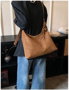 Detail of soft brown suede tote bag with fringe tassels and metallic hardware accent