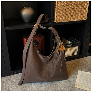 Detail of a dark brown retro dumpling bag with wooden beads and leather flower pendant