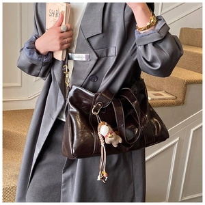Dettaglio tote bag marrone scuro lucido con ciondolo peluche e tracolla in pelle