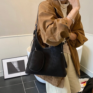 Detail of black suede hobo bag featuring contrast white stitching and a mini pouch