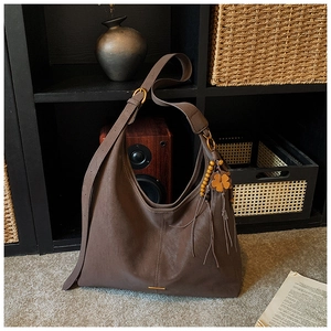 Detail of a brown matte hobo tote bag with vertical stitching and beaded flower charm