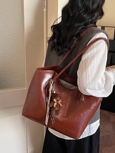 Brown large capacity leather tote bag with plush bear charm and thin shoulder straps
