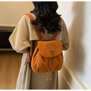 Detail of orange drawstring backpack with embroidered lettering on the top flap