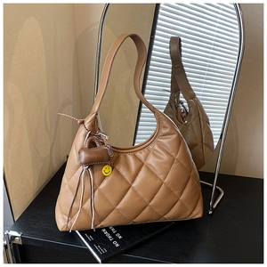 Detail of brown quilted hobo bag with a yellow smiley face charm and heart pendant