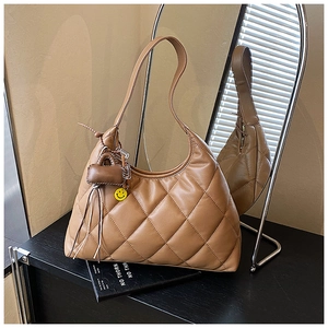 Detail of caramel quilted shoulder bag with heart and smiley face charms on mirror
