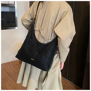 Detail van de gouden balk op de zwarte suède shopper met getextureerde afwerking