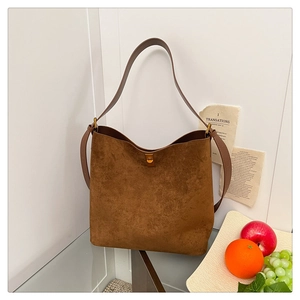 Close-up of brown suede hobo bag with a gold metal turn-lock and adjustable strap