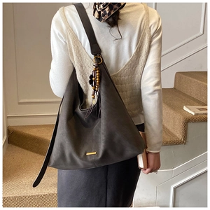 Detail of dark grey tote bag with adjustable strap and floral wooden bead charm