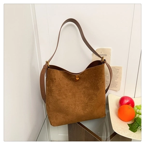 Detail of dark brown suede tote bag with gold twist-lock and wide shoulder strap
