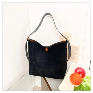 Detail of black suede tote bag featuring smooth leather straps and gold buckle accents