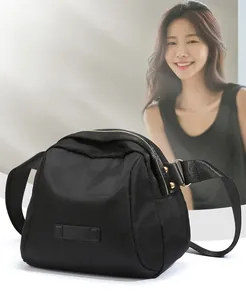 Détail d'un sac bandoulière en nylon noir avec fermetures éclair dorées et style épuré