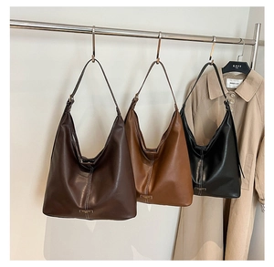 Close-up of three vintage hobo bags in brown, caramel, and black on a metal hanger