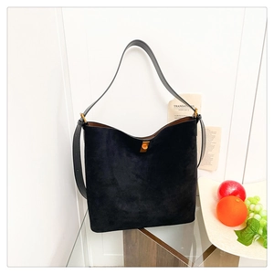 Detail of black suede bucket bag featuring a minimalist design and gold twist-lock closure