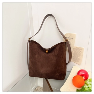 Detailed view of deep brown suede tote bag with leather strap and elegant gold buckle