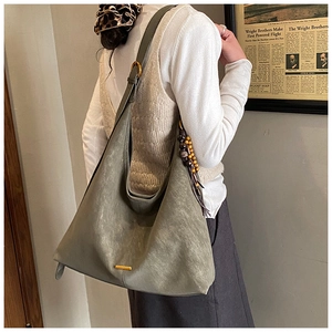 Detail of grey-green suede hobo bag with gold buckle and beaded tassel accessory
