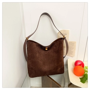 Close-up of brown suede tote bag featuring a vintage metal clasp and wide shoulder strap