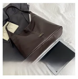 Detail showing white contrast stitching and logo on a dark brown leather tote bag