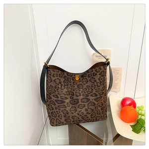 Detail of leopard print tote bag featuring black leather strap and gold metal twist lock buckle
