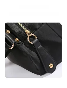 Détail de la fermeture éclair dorée et du tissu en nylon noir sur un sac bandoulière