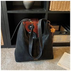 Detail of black matte suede tote bag with four-leaf clover leather charm decoration