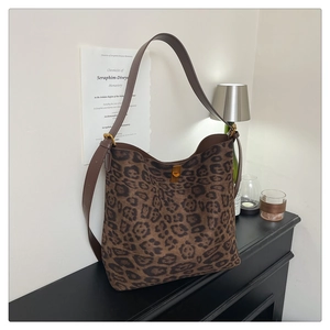Detail of leopard print suede tote bag with golden twist lock on a vintage cabinet