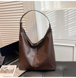 Detail view of the brown leather tote bag with white vertical contrast stitching