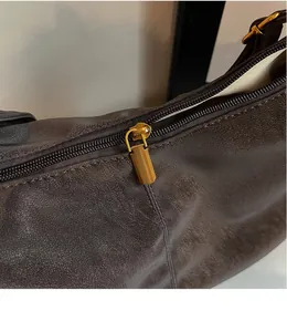 Detail of premium smooth gold zipper and dark brown textured leather on the tote bag
