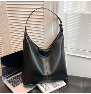 Detail of black Hobo bag with white stitching and metallic brand plaque on its front