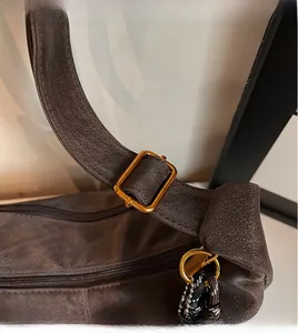 Detail of brown matte leather shoulder bag with gold metal buckle and zipper closure