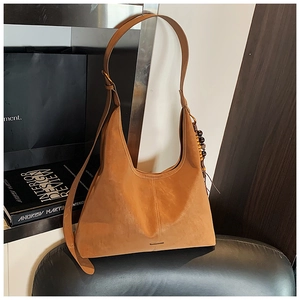 Detailed macro view of camel suede hobo bag with ethnic wooden bead charm detail