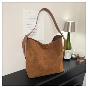 Detail of suede bucket bag featuring metallic buckle and vintage caramel brown finish