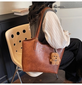 Detail of vintage brown tote bag with adjustable strap and cute plush bear charm
