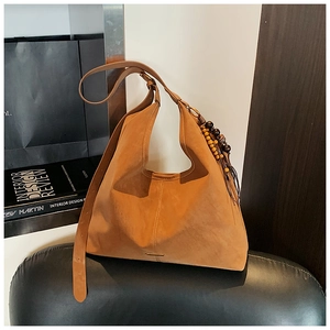 Detail of warm brown suede tote bag featuring a vintage wooden bead tassel charm