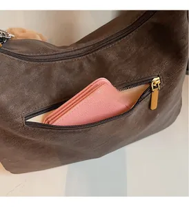 Detail of coffee brown lychee pattern leather shoulder bag showing front zipper pocket capacity