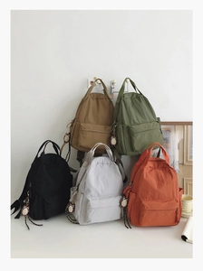 Five minimalist nylon backpacks in various colors featuring cute owl keychain details