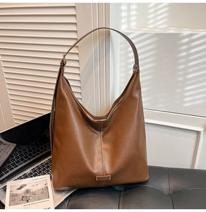 Close-up of brown leather hobo bag with center stitching and metal logo plate