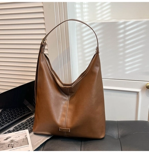 Detailed close-up of brown hobo bag with white stitching on a leather surface