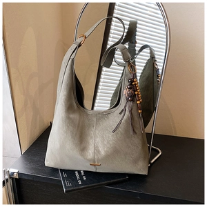 Detail of grey matte leather tote bag with wooden bead charm and gold hardware accents