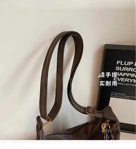 Detailed close-up of adjustable shoulder strap and gold buckle on brown suede tote bag