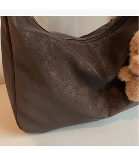 Detail of dark brown hobo bag showing soft vintage leather texture and cute bear charm