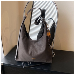 Close-up of matte grey hobo bag with gold hardware and lucky clover charm detail