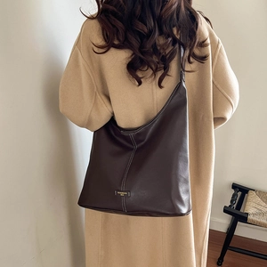 Detailed view of deep brown hobo bag with white contrast stitching and gold logo