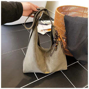 Close-up of moss green leather tote bag with wooden bead charm and metallic ring
